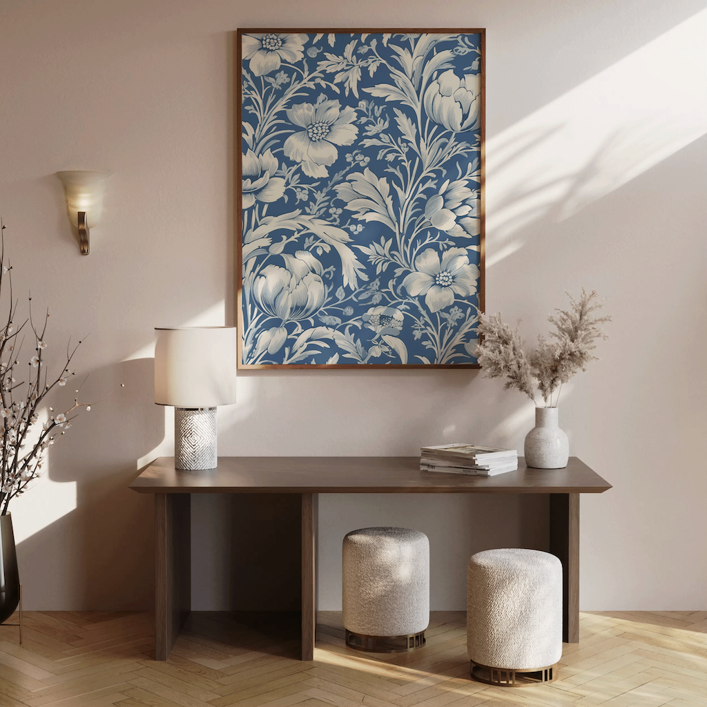 Decorative floral painting above a wooden table with a lamp and books in a room with sunlight streaming in.