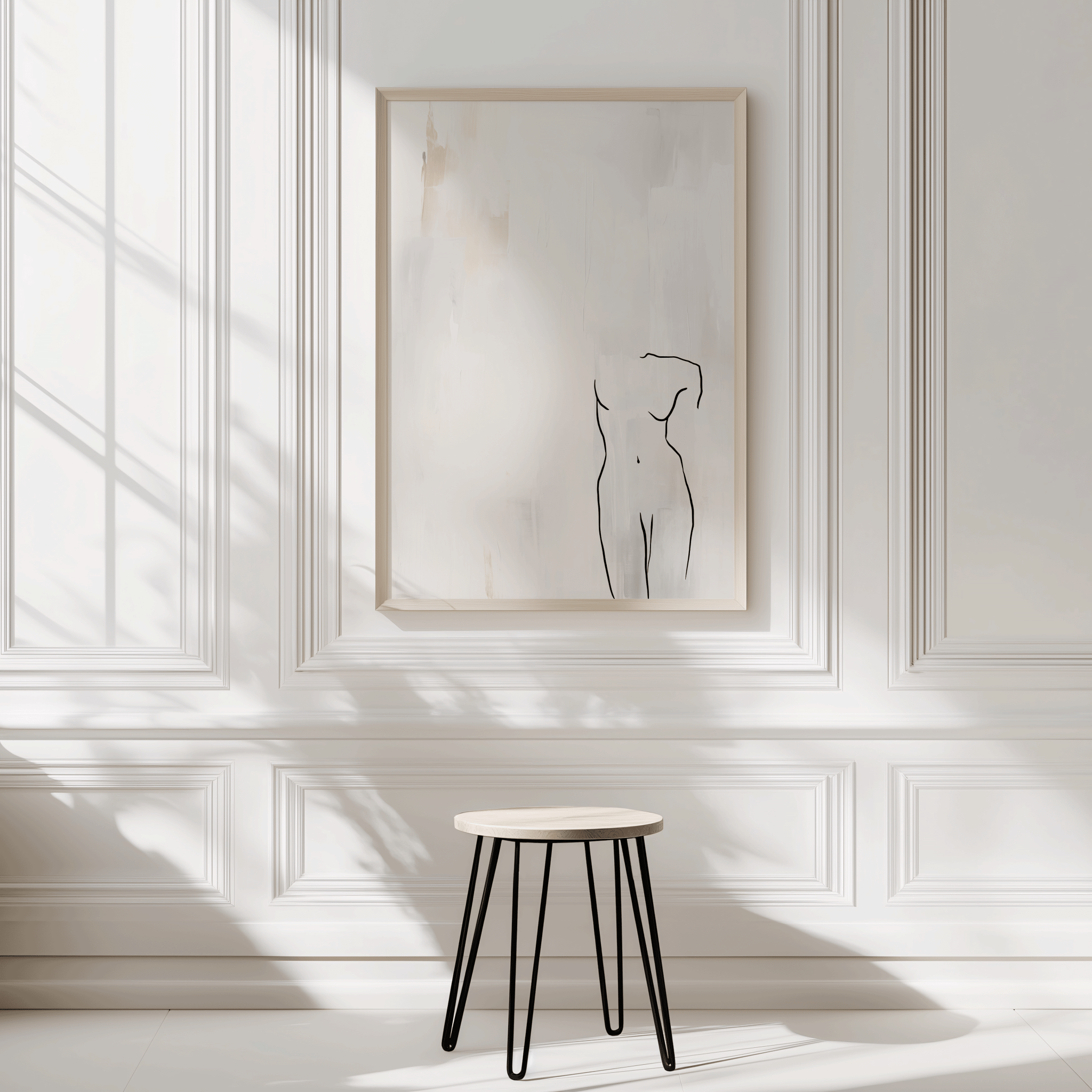 Beige frame line art wall decor with minimalist female form drawing displayed on white panel walls with soft shadows and minimalist stool underneath