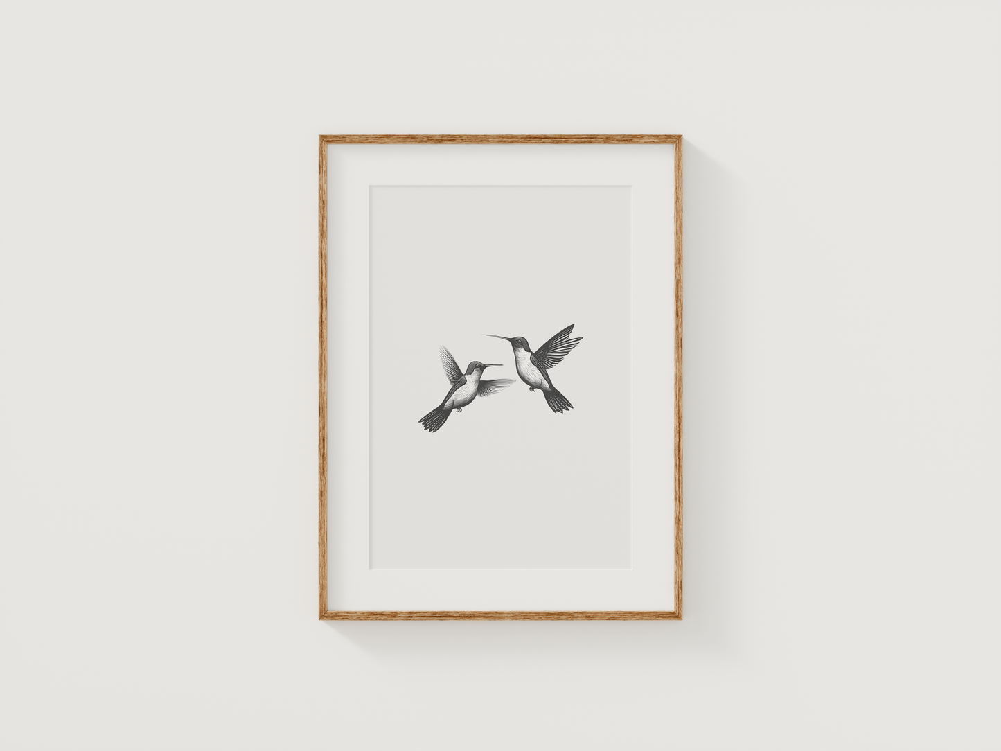 Minimalist hummingbird wall art in black and white framed with natural wood displayed on a neutral wall