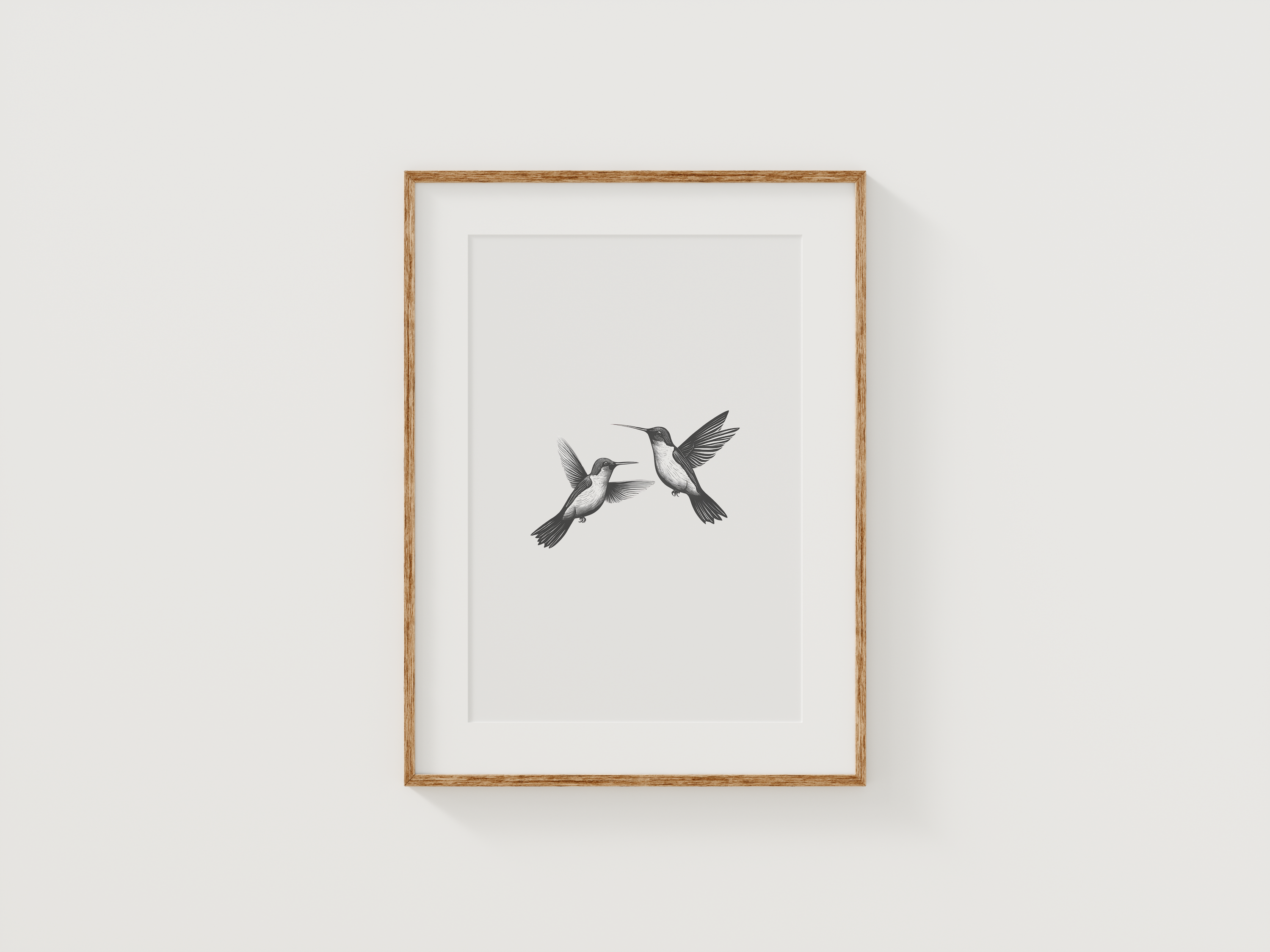 Minimalist hummingbird wall art in black and white framed with natural wood displayed on a neutral wall