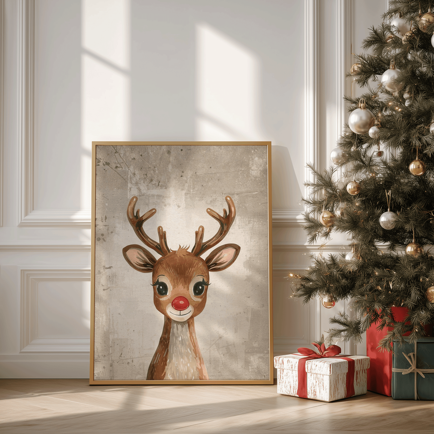 Framed Rudolph reindeer Christmas wall art leaning against a wall beside a decorated Christmas tree with red and gold ornaments and wrapped presents, styled in a neutral living room with warm natural light.