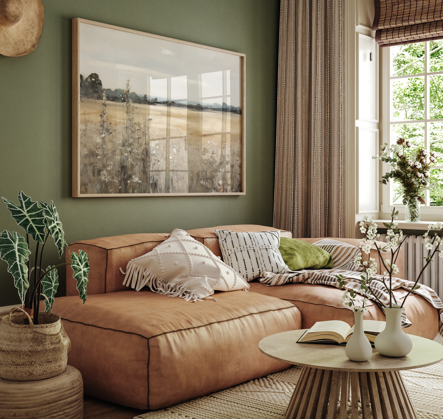 Vintage countryside landscape wall art framed canvas print on a green wall above a camel brown leather sofa in cozy living room.