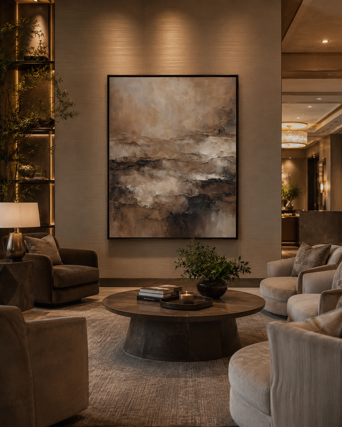 Large framed abstract wall art in moody brown, taupe, and cream tones as the focal point in an upscale hotel lobby lounge, an example of commercial wall art sourced for a hospitality project