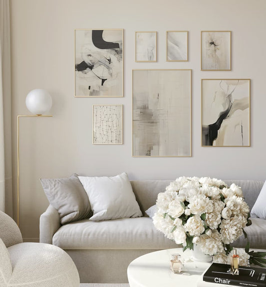 Neutral gallery wall of framed abstract and line art prints above a white sofa in a living room