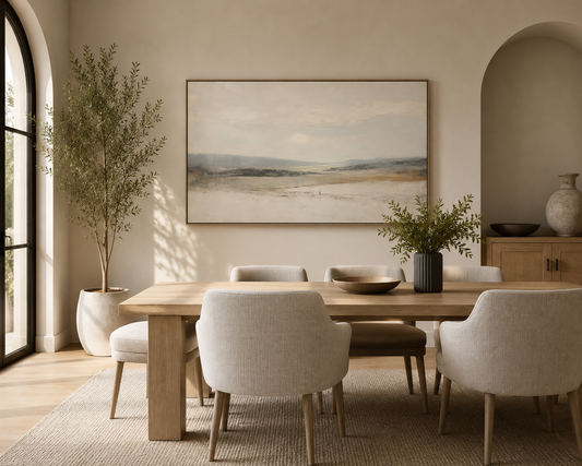 Large neutral vintage landscape wall art in a contemporary dining room featuring light oak furniture, upholstered dining chairs, warm beige walls, and soft natural daylight.