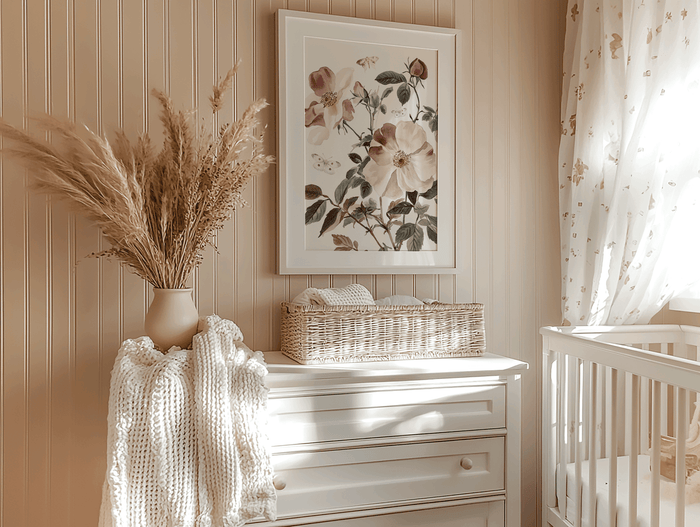 Nursery wall art placement above dresser with framed botanical print, pampas grass, and crib in neutral tones