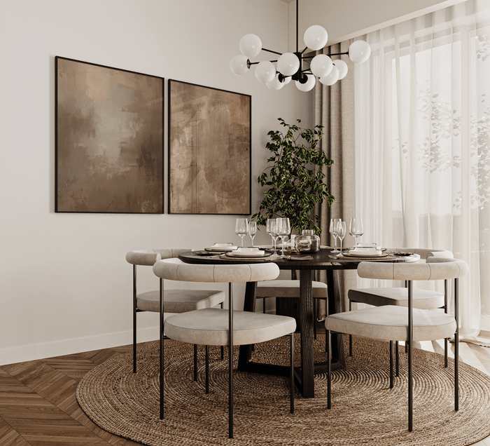 pair of neutral abstract wall art prints in warm brown and beige tones styled above a modern dining room table with light upholstered chairs, woven round rug, greenery and soft natural daylight
