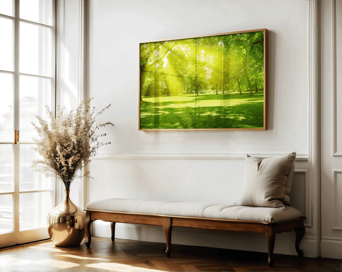 Sunlit forest and meadow print above a linen bench in a classic entryway with a gold vase