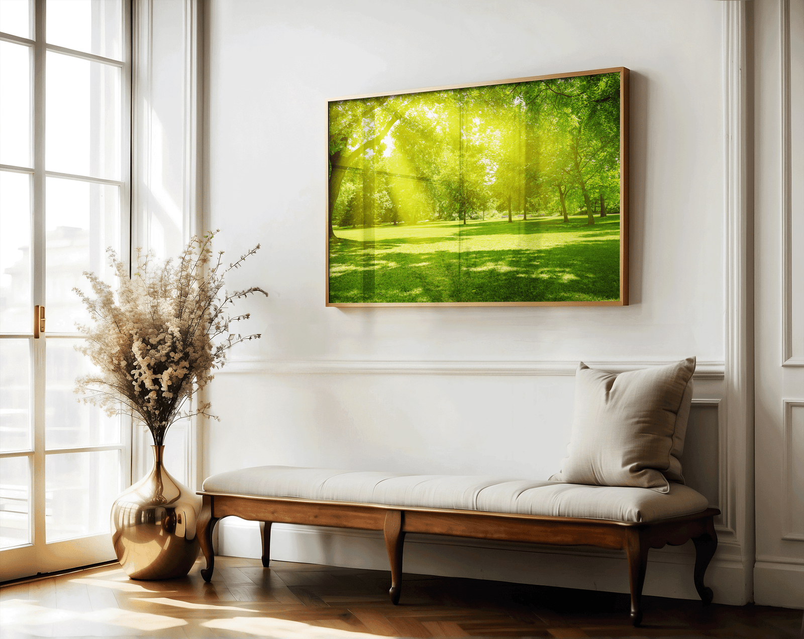 Large nature landscape art with sun rays over grassy park, styled above linen bench in classic entryway with gold vase and floral accents, inviting biophilic home decor