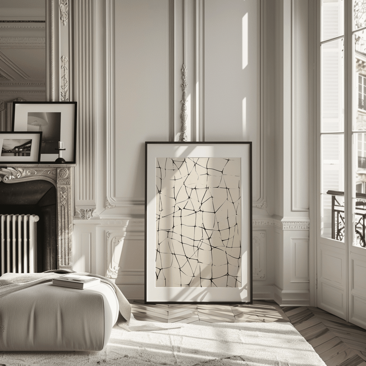 Large abstract line grid wall art in black on beige leaning on the floor in a classic Parisian-style room with fireplace, tall windows, and decorative molding