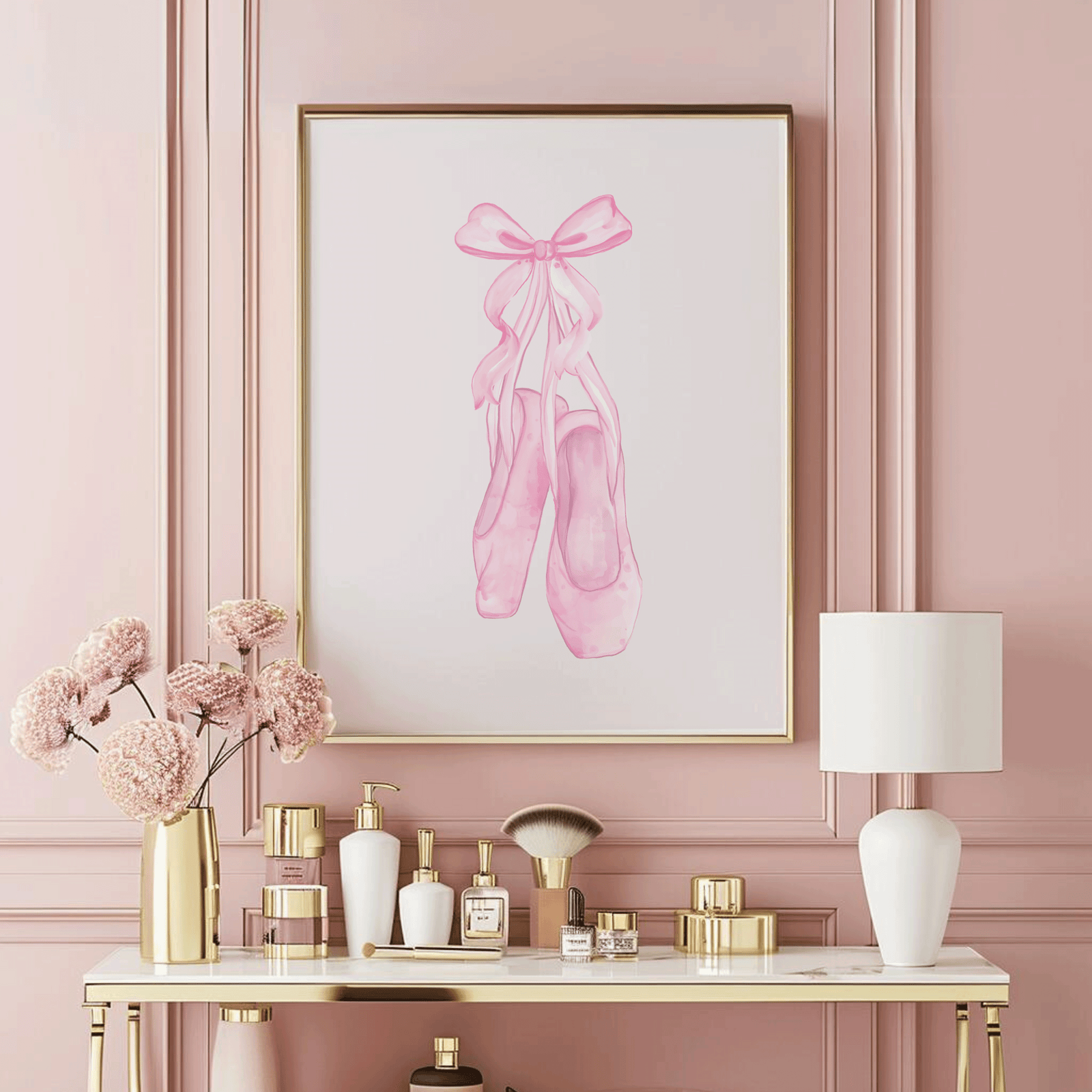 A framed art print featuring a watercolor illustration of pink ballet slippers, displayed on a pink wall above a styled vanity table.