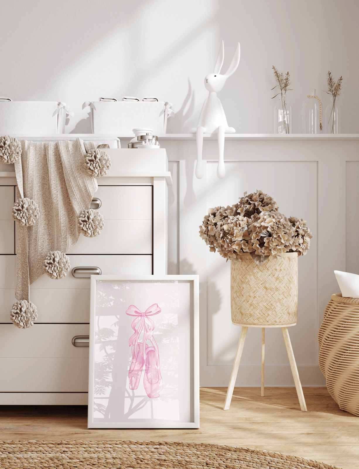 A framed art print featuring pink ballet slippers with pink coquette bow, in a nursery setting next to white dresser