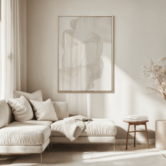 Beige and cream abstract line wall art print with a light wooden frame showing subtle faux textured linear waves in a neutral, minimal living room above a cream sectional sofa.