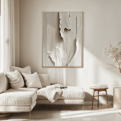Modern living room with a neutral color palette, featuring a sofa, minimal abstract wall art with a wooden frame and white and beige tones, and minimal decor.