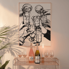 Black and white cheers print in a natural frame above a glass bar cart with wine bottles and candles