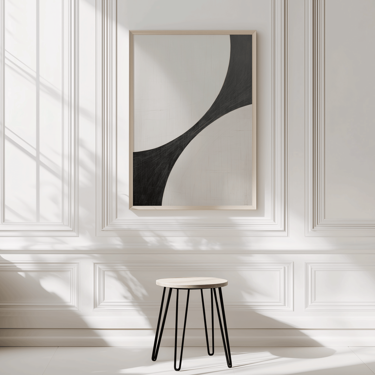 Minimalist curve abstract in a light wood frame on a white wainscoted wall with a small stool in sunlight.