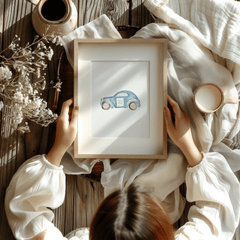 Child holding a framed blue watercolour car print on a cozy blanket