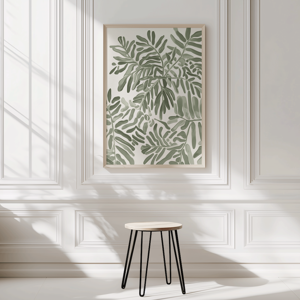 Neutral botanical leaf wall art shown as a single centered print in a light wood frame, mounted on a decorative paneled wall above a small stool