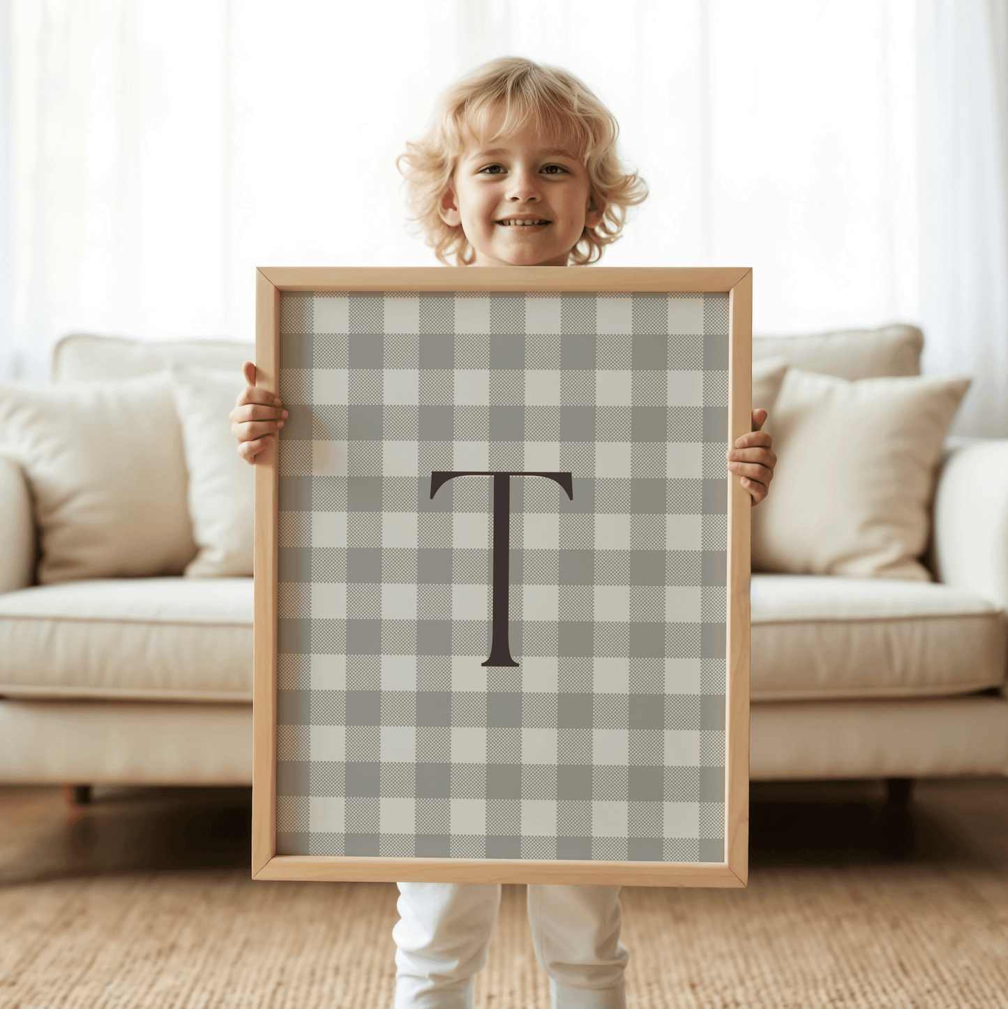 young boy holding personalized beige gingham monogram print with serif letter T, modern neutral nursery wall decor