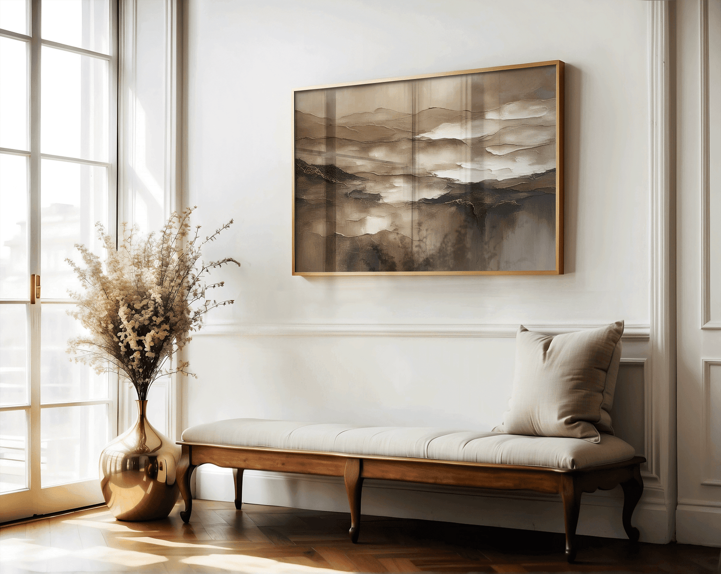Brown abstract wall art in a gold frame above an upholstered entryway bench