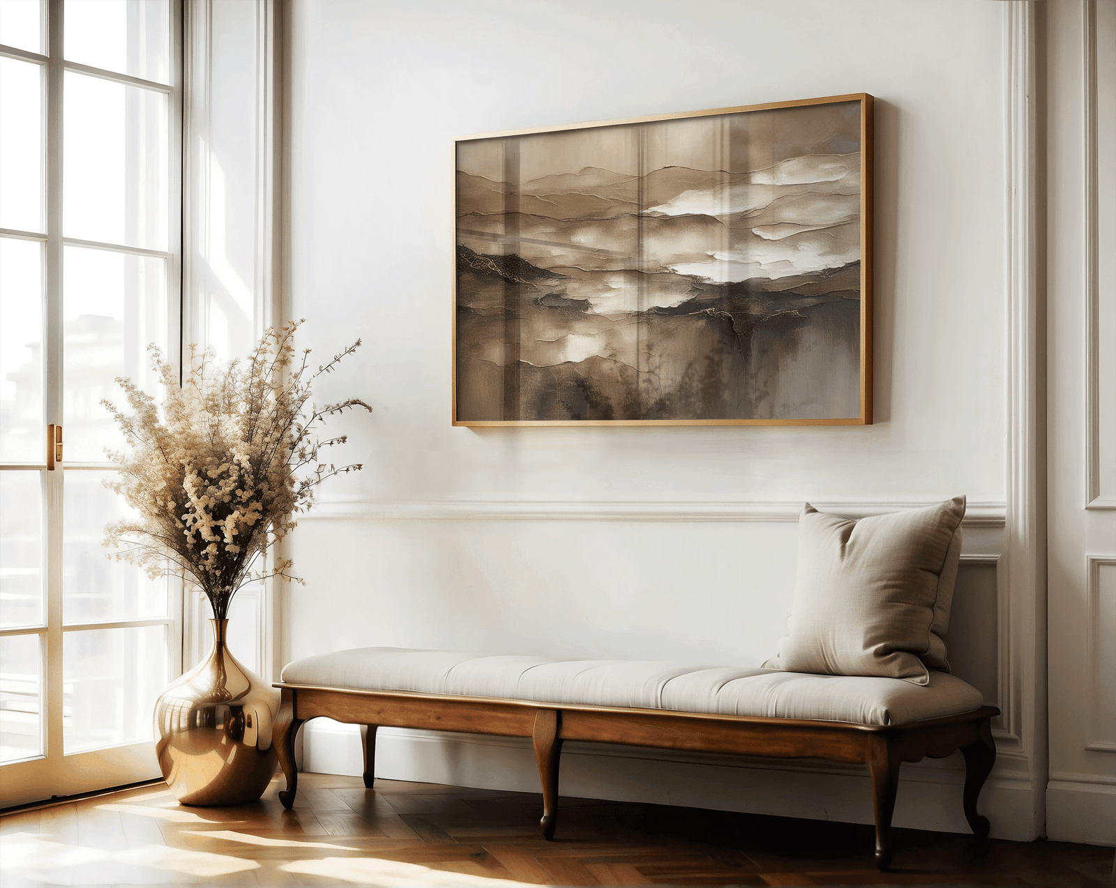 Brown abstract wall art in a gold frame above an upholstered entryway bench