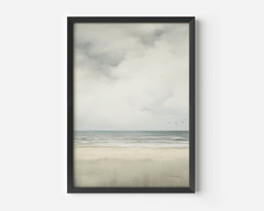 Framed neutral ocean and sky landscape wall art with a black frame on a white wall
