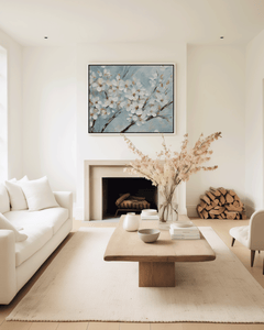 Large cherry blossom wall art with white flowers on a blue background framed above a fireplace