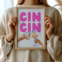 Woman in a cream sweater holding a framed pink cin cin cocktail print