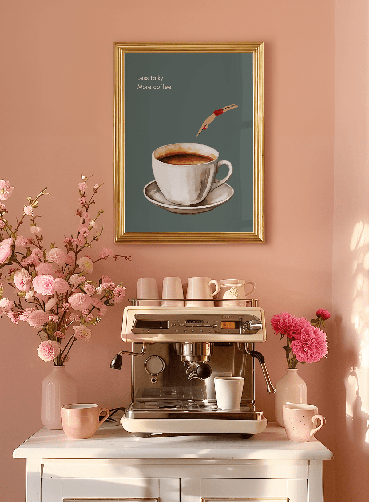 Coffee bar wall art in a gold wood frame on a peach wall above an espresso machine with pink blossoms