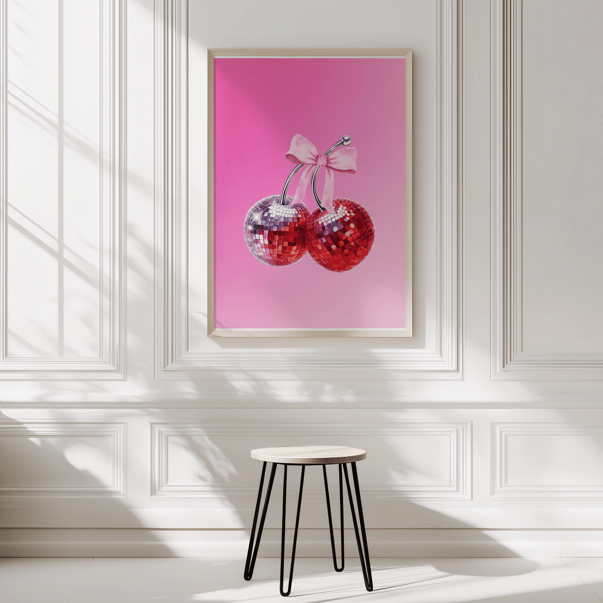 Coquette cherry print in a natural frame on a white panelled wall above a black stool