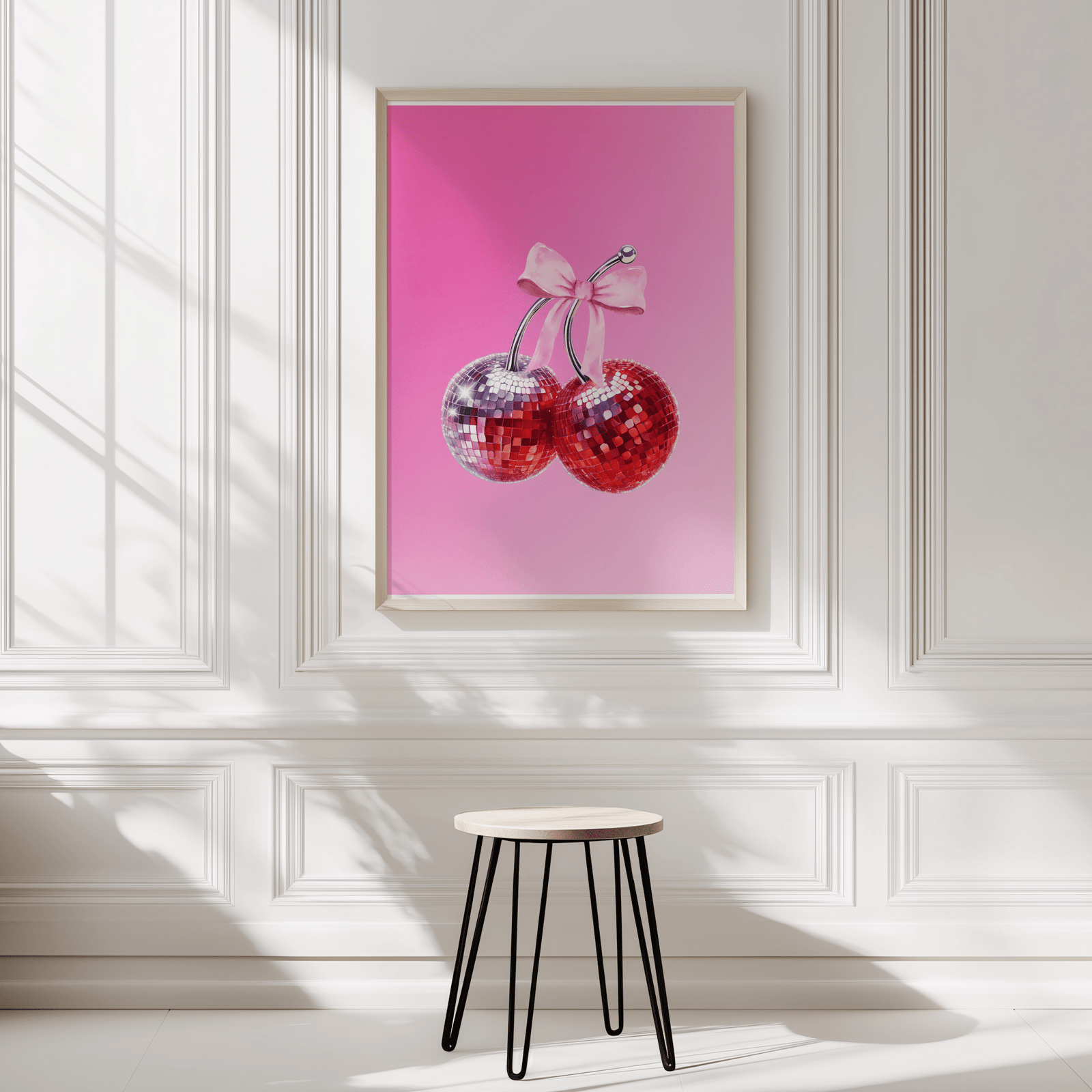Coquette cherry print in a natural frame on a white panelled wall above a black stool