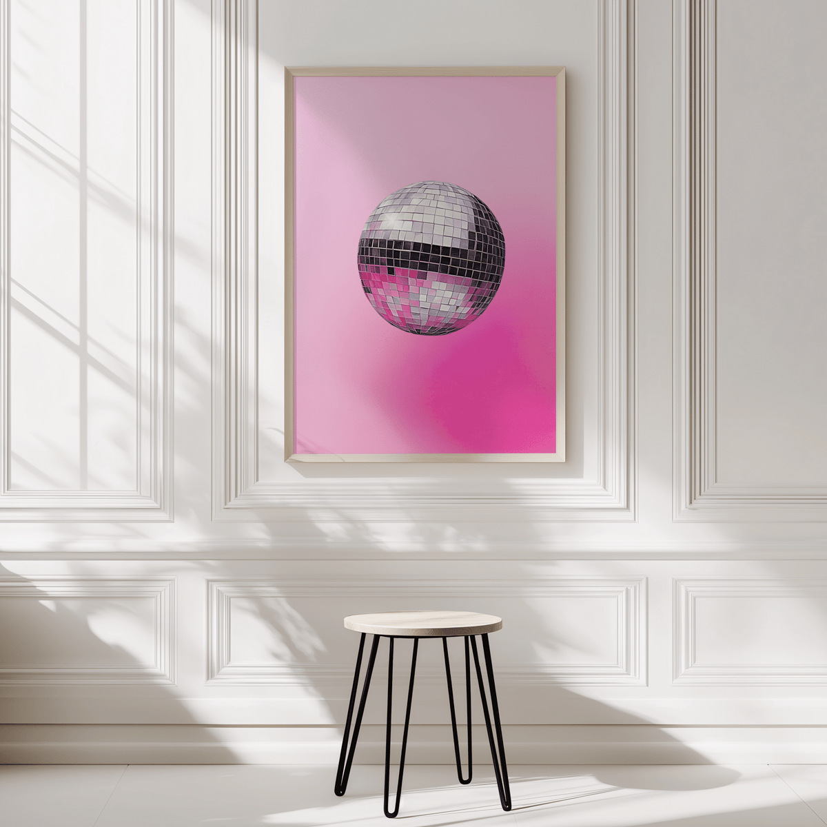 Disco ball print in a natural wood frame on a white panelled wall above a black stool