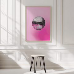 Disco ball print in a natural wood frame on a white panelled wall above a black stool