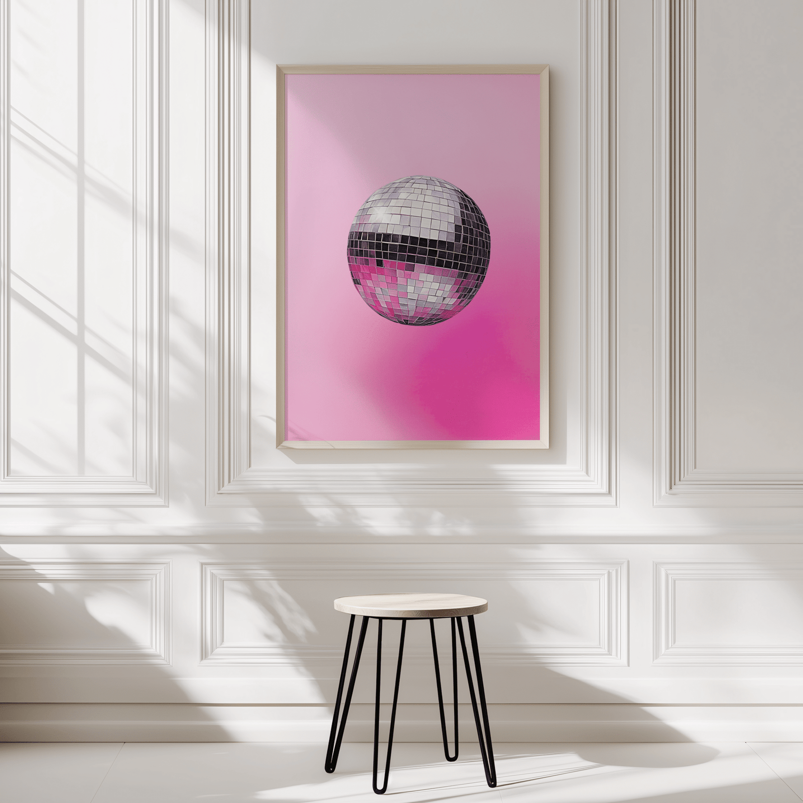 Disco ball print in a natural wood frame on a white panelled wall above a black stool