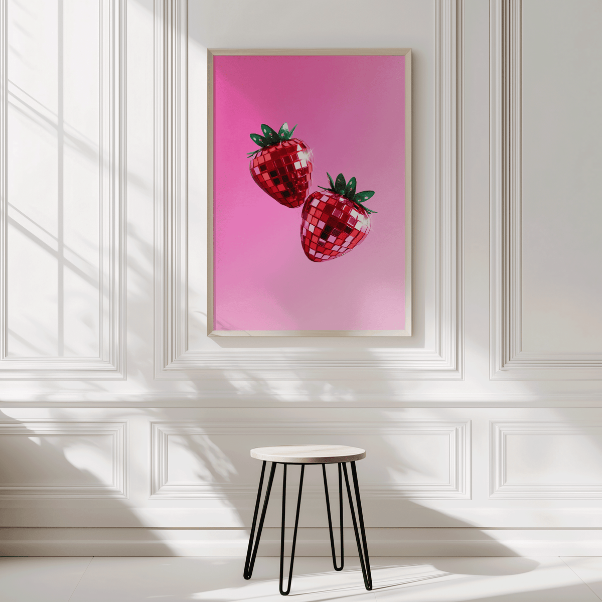 Disco strawberry print in a natural frame on a white panelled wall above a black stool