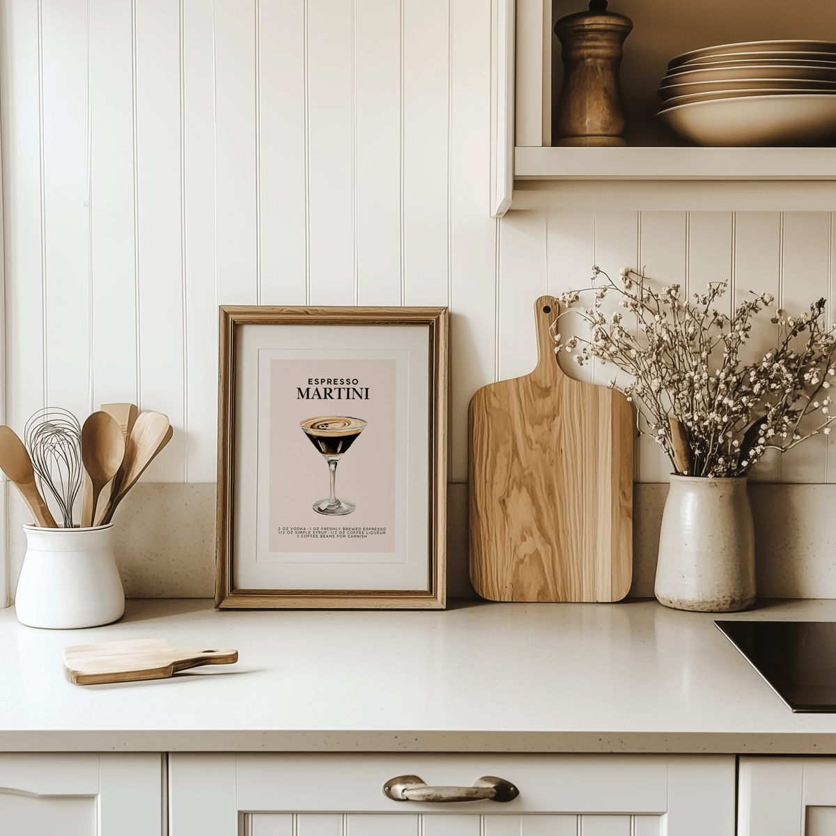 Espresso martini cocktail print in a natural wood frame on a white kitchen counter beside a cutting board