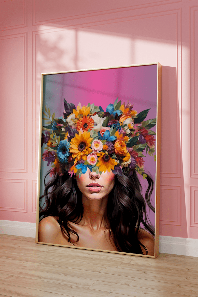 A modern woman portrait art print framed with a bright flower head crown and artistic color palette. Bold colors and vibrant flowers covering a woman's eyes on her head with an ombre pink background on a pink wall.