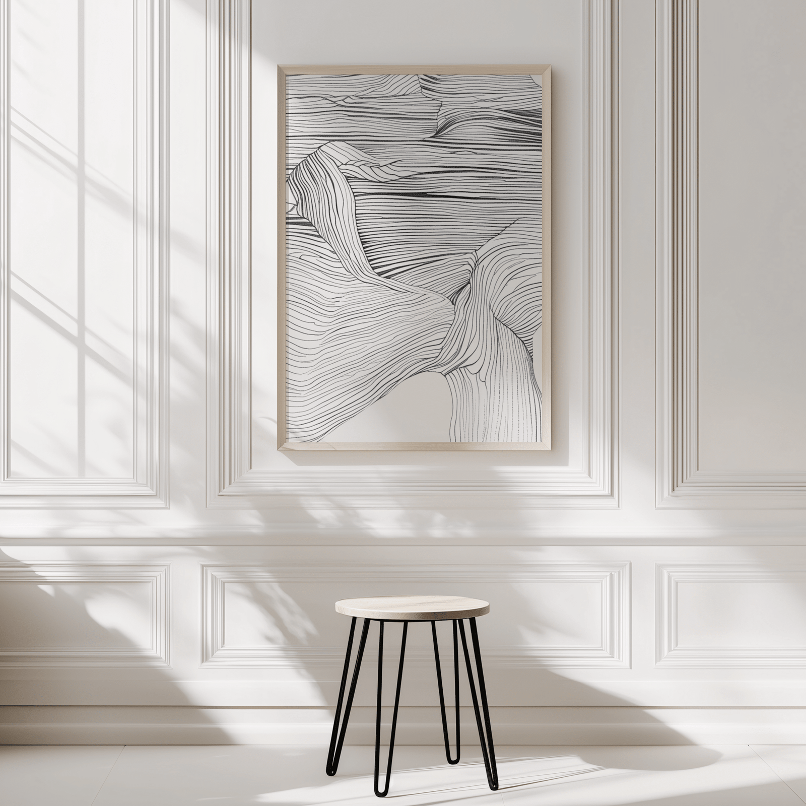 Modern abstract line art print framed in black and white on a minimalist white panelled wall with a small stool in front 