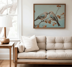 Beige sofa with decorative pillows in a living room setting, featuring a framed vintage wall art print of birds on a branch.