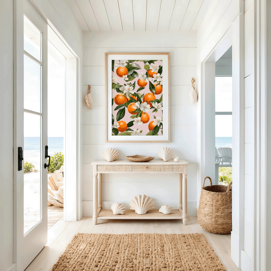 Citrus orange wall art framed above light wooden console table in a beach house or cottage hallway or entryway with ocean views