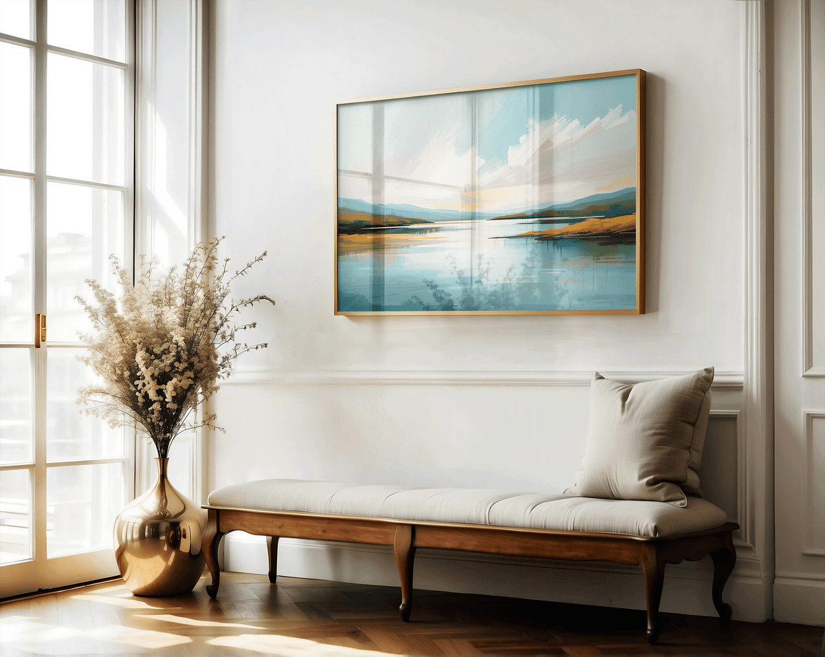 Framed coastal landscape wall art with soft blue tones in elegant entryway above a bench