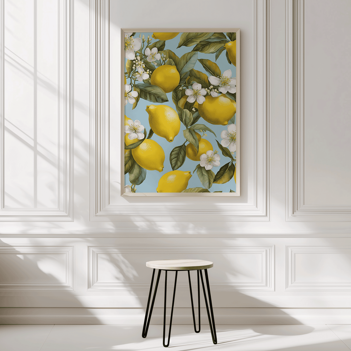 Lemon botanical wall art framed in gold against a bright white panelled wall with minimalist stool underneath