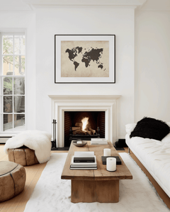 Framed world map wall art over a white fireplace in a modern, neutral living room with wood accents