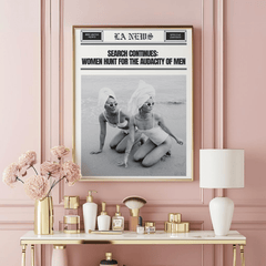 Funny feminist newspaper wall art in a natural frame on a pink wall above a gold vanity with perfume bottles and flowers