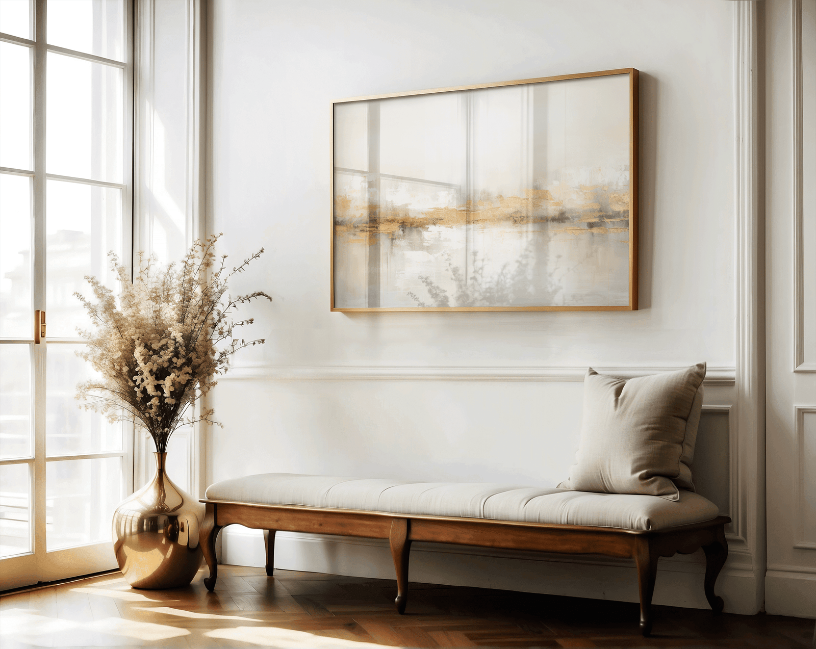 Neutral beige and gold abstract wall art framed in gold above hallway bench with cushion and vase decor