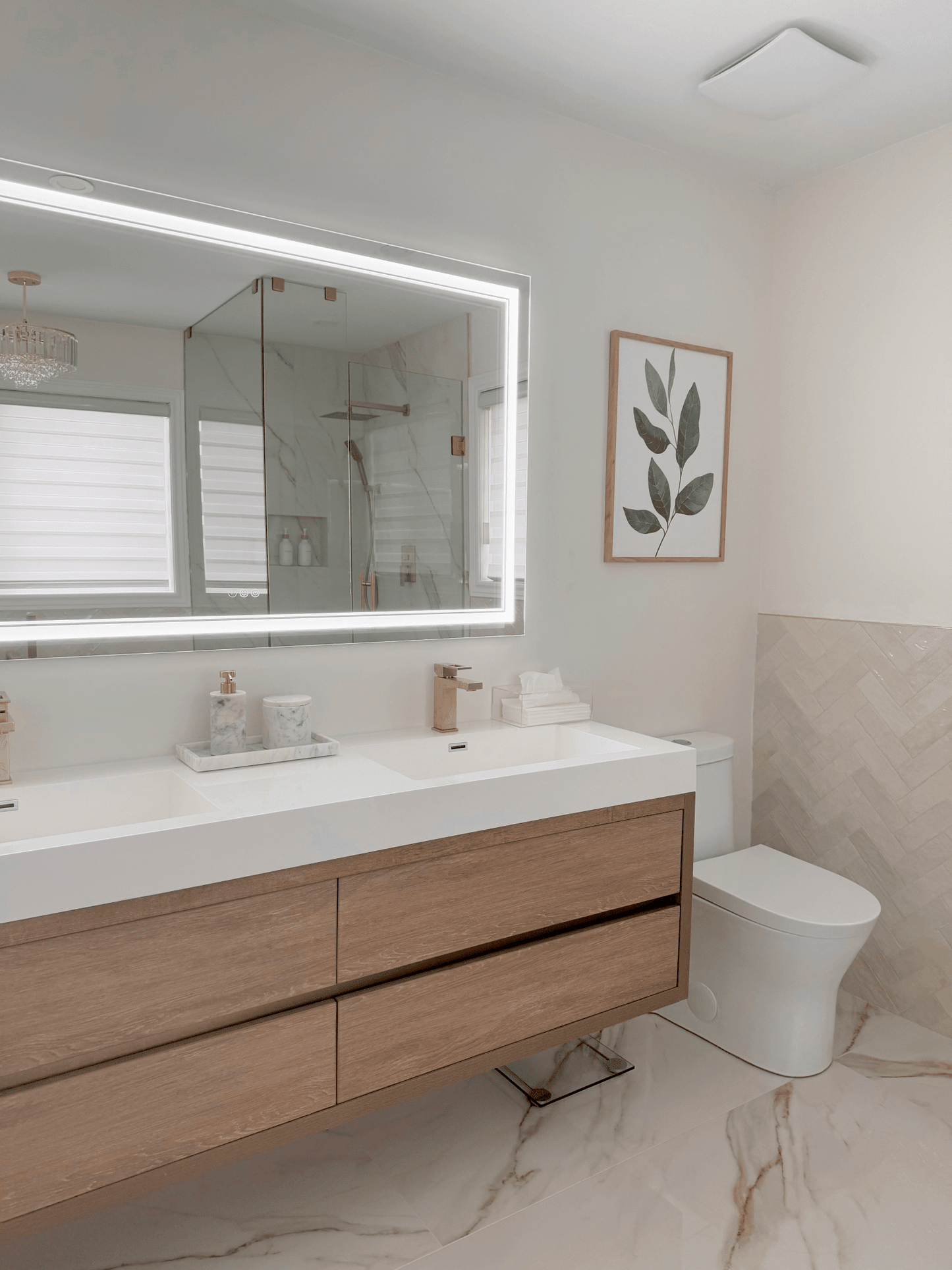 Green leaf wall art in an oak frame above a vanity in a modern marble bathroom
