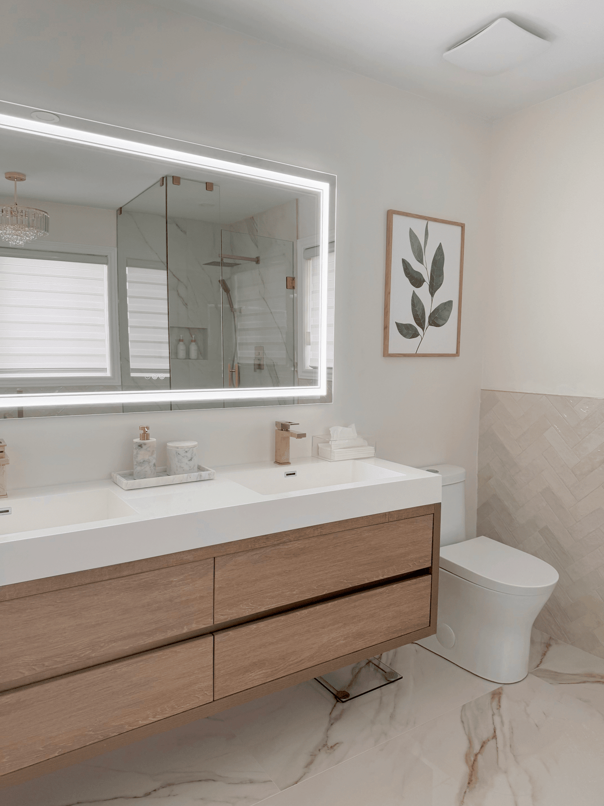 Green leaf wall art in an oak frame above a vanity in a modern marble bathroom