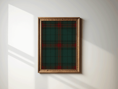 Green and red plaid wall art in a brown wood frame on a sunlit white wall