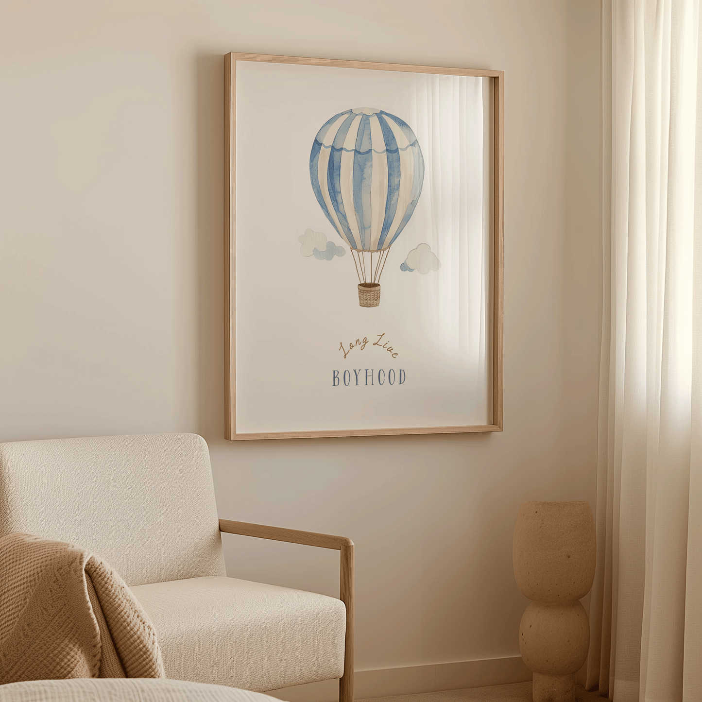 Blue hot air balloon boy nursery wall art in an oak frame above a cream armchair