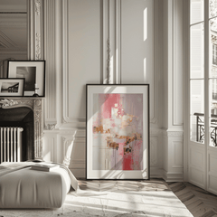 Large pink and gold metallic abstract wall art framed with a black frame on the floor up against the wall in a modern, neutral living room next to a fireplace.
